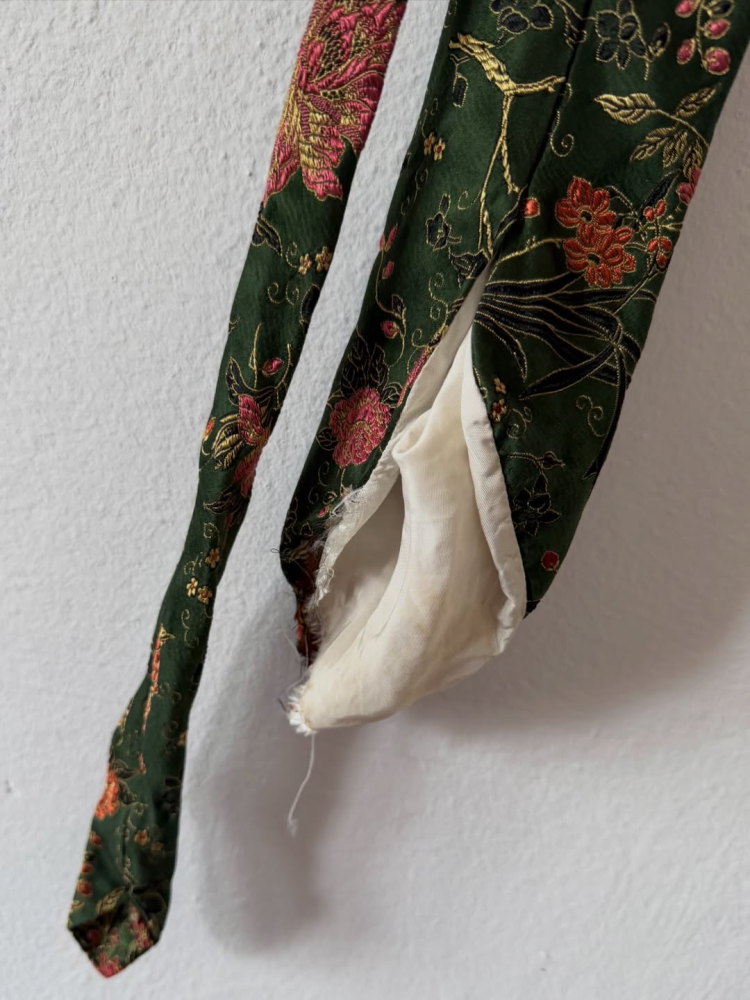 Damaged silk tie inherited from grandfather, close-up of torn seams and worn fabric